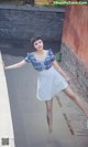 A woman in a blue and white dress leaning against a wall.