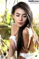 A woman with long black hair sitting on a wooden bench.