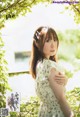 A woman in a white dress standing in front of a tree.