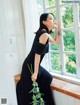 A woman in a black dress sitting on a window sill.