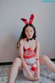 A woman sitting on the floor wearing a red bunny costume.