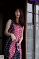 A woman standing in front of a window wearing a dress.